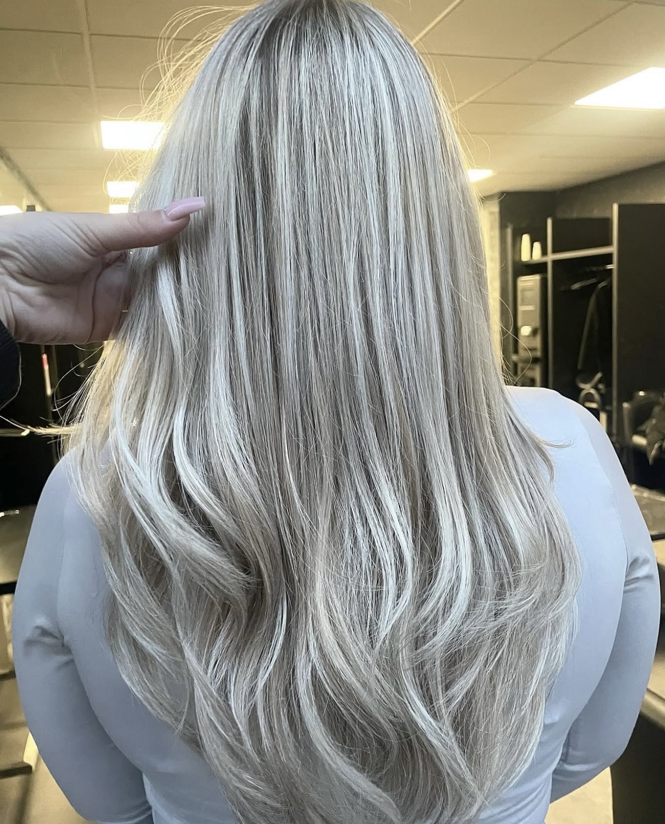 Lang platinablond haar met balayage, achteraanzicht in de salon